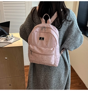 Pink fashion backpack with silver star print on model in cozy indoor setting