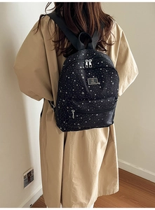 Close-up of black backpack with white star patterns and front zipper pocket detail