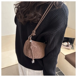 Détail du sac selle marron à motif léopard avec bandoulière à nœuds élégante