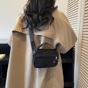 Sac bandoulière minimaliste en nylon noir avec sangle réglable et logo argenté
