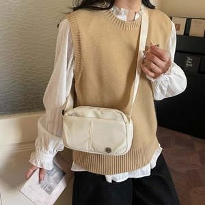 Minimalist cream nylon crossbody bag with adjustable strap and front pocket detail