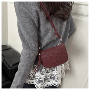 Détail du petit sac bandoulière bordeaux avec gaufrage léopard porté par un mannequin