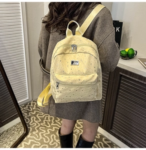 Side view of a light yellow backpack with silver star patterns on a female model