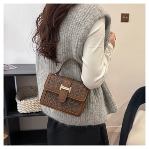 Detail of vintage brown monogram handbag with golden H-clasp and elegant top handle