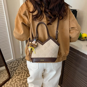 Minimalist beige canvas bucket bag with brown leather trim and cute bear charm pendant