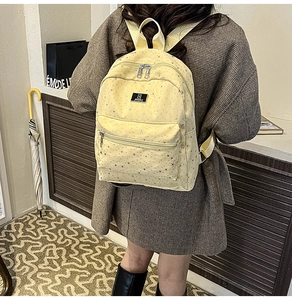 Lifestyle view of light yellow star pattern canvas backpack on a model for size reference