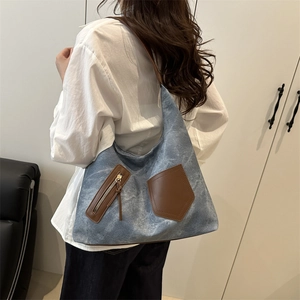 Chic blue denim hobo bag with brown leather pockets and wide shoulder strap