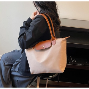 Close-up of nylon tote bag featuring a leather flap with metal snap button closure