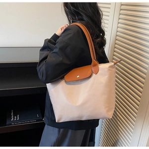 Detail view of beige nylon tote bag with brown leather flap and long shoulder handles