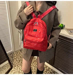 Detail view of a red star pattern backpack with silver stars and front zipper pocket