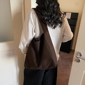 Grande borsa tote minimalista in tela marrone con ampia tracolla indossata da un modello