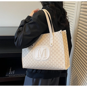 Detail of PU leather tote with monogram M prints and embossed logo on beige background