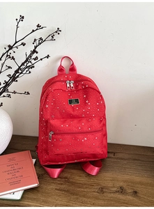 Detail view of the red backpack featuring silver star patterns on wooden surface