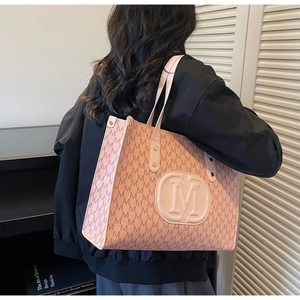 Detailed view of pink monogram tote bag with textured M logo and rivet handle design