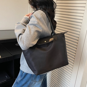 Black large capacity nylon tote bag with leather trim and button closure on model