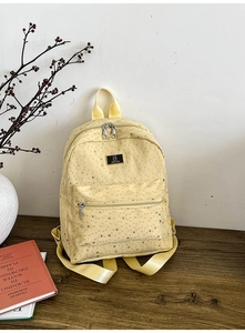 Detail of light yellow backpack featuring silver star patterns and JUHAI metal brand plate