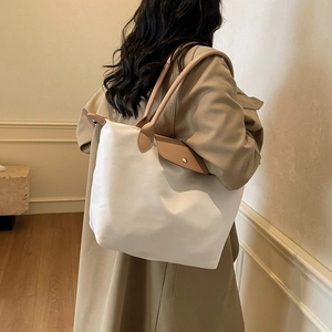 Minimalist white nylon tote bag with brown leather handles and gold snap button closure
