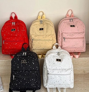 Detail of star pattern backpacks in multiple colors with front zip pockets