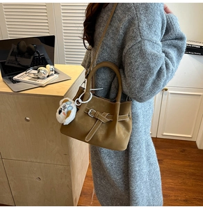 Détail du sac bandoulière marron en suédine avec sangle décorative et breloque koala