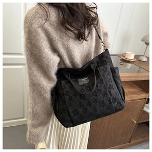 Detail of black floral embossed tote bag with adjustable strap and fashion label tag