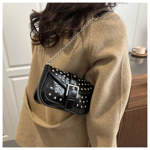Close-up of black rivet shoulder bag with silver chain strap on a camel wool coat