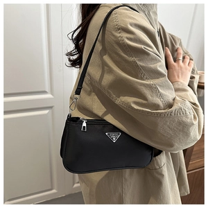 Detail of black nylon shoulder bag with triangle logo and silver zipper on model