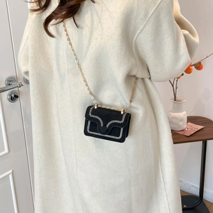 Mini sac bandoulière noir avec broderie blanche et chaîne dorée sur manteau doux