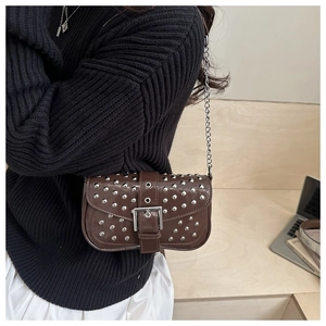 Close-up of punk style dark brown handbag featuring silver rivets and metal chain strap