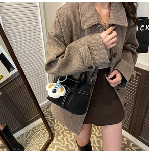 Détail d'un sac à main en daim noir avec un joli pendentif chiot en peluche blanc