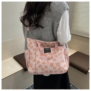 Detail of pink floral canvas tote bag featuring dual handles and adjustable shoulder strap