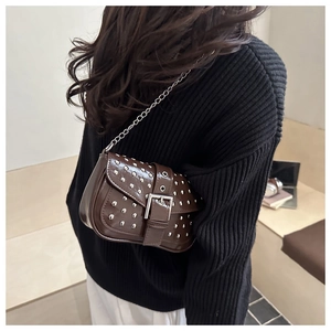 Brown rivet shoulder bag with silver studs and chain strap shown on model's shoulder