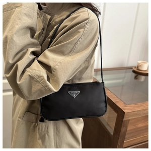 Detailed view of a black nylon baguette bag with triangle logo and slim shoulder strap