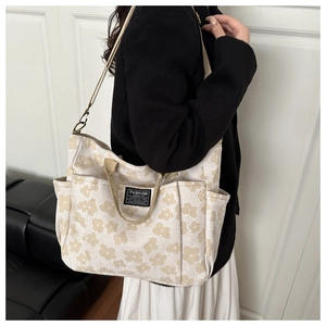 Detail of floral canvas tote bag with fashion label and adjustable crossbody strap