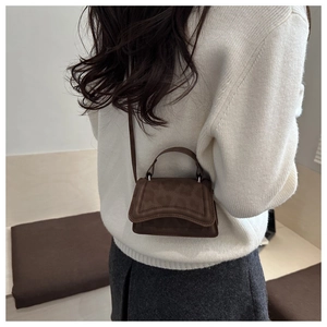 Vista posteriore di una modella con la mini borsa a tracolla in pelle scamosciata marrone