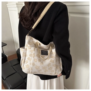 Detail of floral canvas tote bag showing side pocket and woven shoulder strap