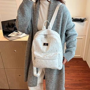 Stylish white backpack with silver star pattern shown in a modern home office setting
