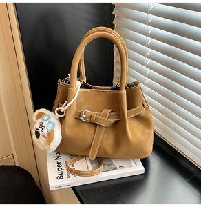 Détail du sac à main en daim marron avec pendentif koala en peluche et boucle de ceinture