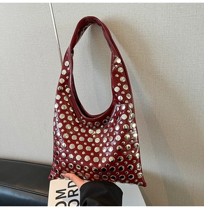 Détail du sac bandoulière en cuir verni rouge foncé avec rivets métalliques argentés