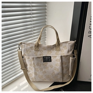 Close-up of beige canvas tote bag featuring floral jacquard texture and multiple pockets