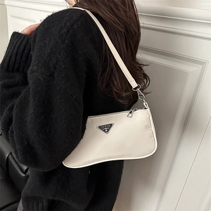 Minimalist white nylon shoulder bag with triangle logo worn by model on shoulder
