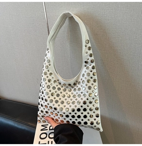 Gros plan des rivets argentés sur le cuir verni blanc du sac à bandoulière gothique