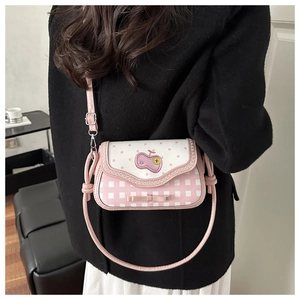 Pink and white patterned crossbody bag shown styled with a black wool coat for a chic look