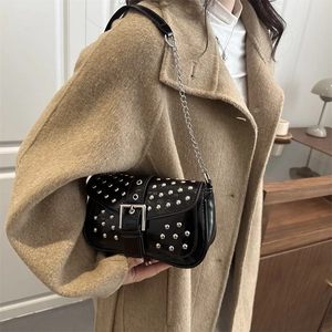 Punk style black rivet shoulder bag with silver studs and chain strap on a model