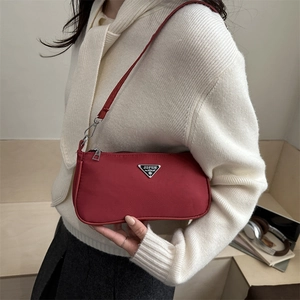 Minimalist red nylon underarm shoulder bag with iconic silver triangle logo plaque