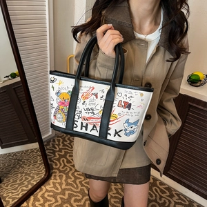 Chic tote bag with hand-drawn graffiti and black leather trim for modern fashion
