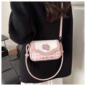Detail of pink plaid crossbody bag with apple patch and decorative bow accents