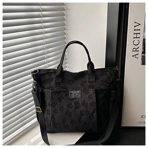 Detail of black tote bag with embossed floral texture and Fashion Instinct label