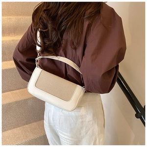 Detail of color-block baguette bag featuring beige weave and white leather frame
