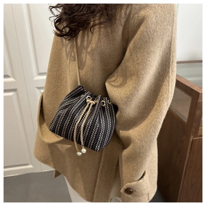 Detail of herringbone tweed bucket bag with drawstring closure and pearl accents