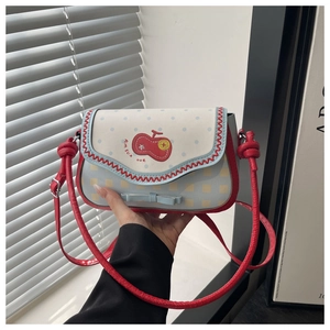 Detail of a mini apple-themed crossbody bag with polka dots and red wavy stitching